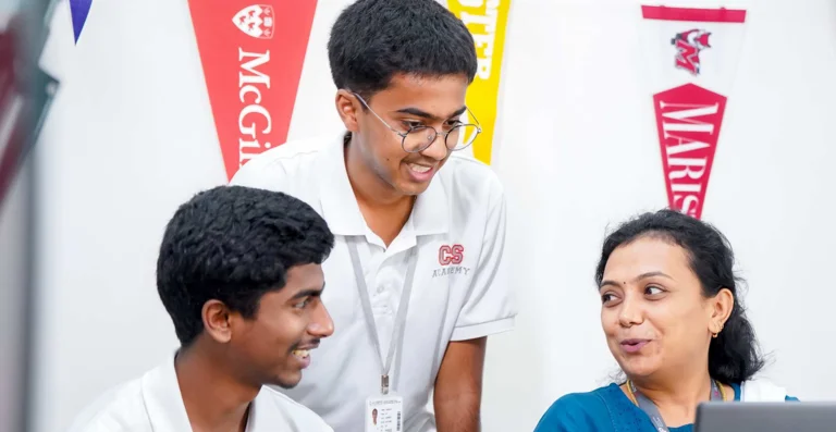 Counselor explaining university options to two students on laptop, with college pennants including McGill and Laurier on wall
