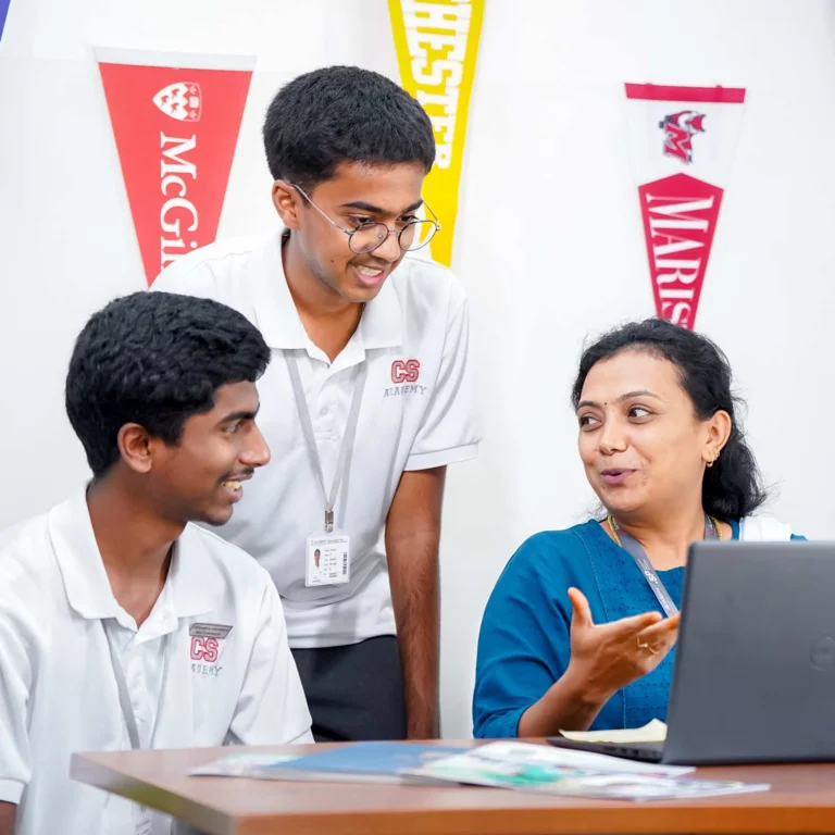 Counselor explaining university options to two students on laptop, with college pennants including McGill and Laurier on wall